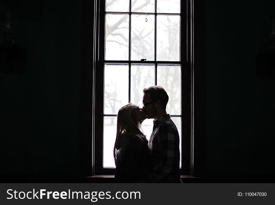 Man and Woman Kissing Beside Window