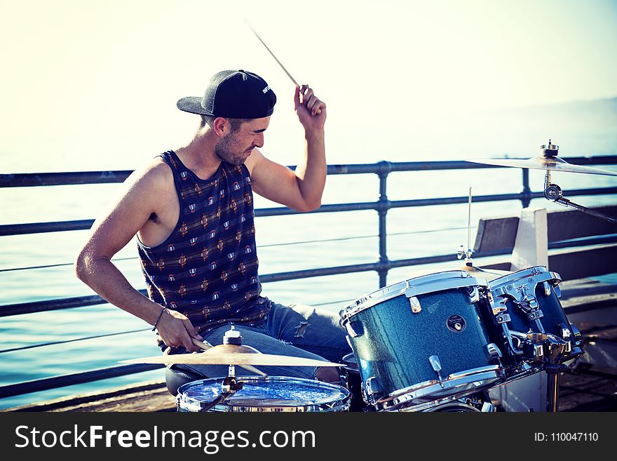 Man Playing Drum Near Bay at Day Time