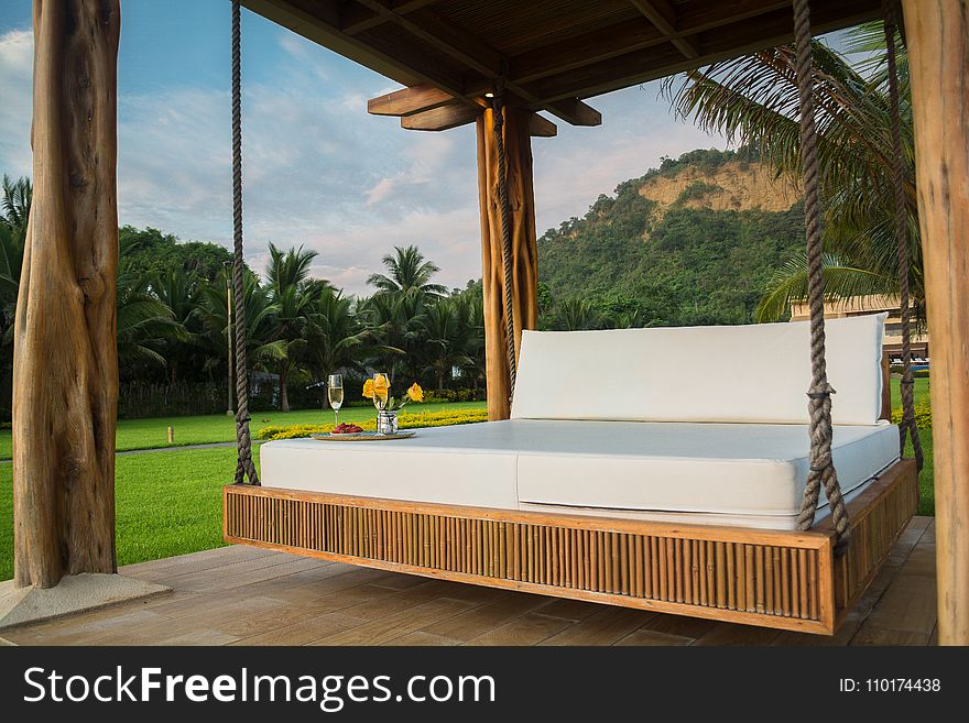 Brown Wooden Framed With White Mattress Hanging Bed Surrounded by Green Grass