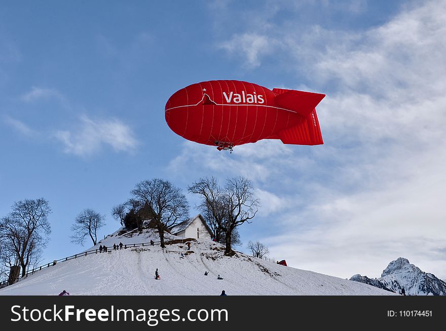 Red Valais Blimp Above White Wooden House