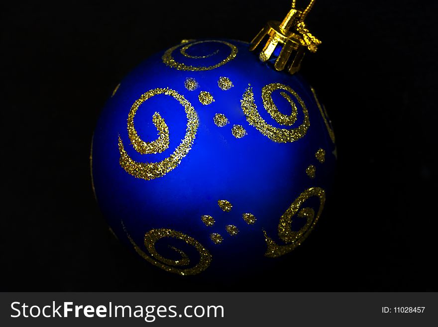 A blue glass Christmas bauble painted with gold sparkly paint. A blue glass Christmas bauble painted with gold sparkly paint