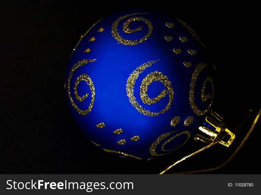 A close-up of a blue and gold christmas decoration against black. A close-up of a blue and gold christmas decoration against black