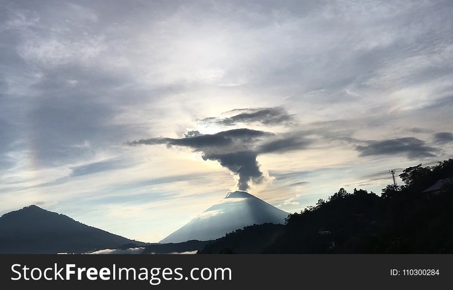 Sunrise above Lake Batur Covered with Clouds and Mount Agung Erupting Smoke - Seen from Top of Mount Batur in Bali in Indonesia.