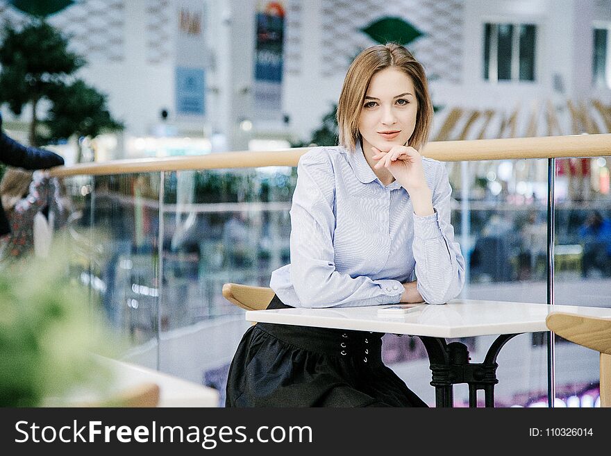 A young woman talking through the phone. The girl is sitting at the table and makes an order. Business woman
