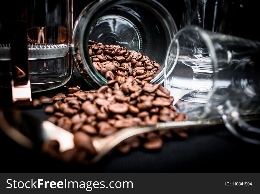 Coffee Beans Spoiling on Clear Glass Jar Near Clear Glass Mug