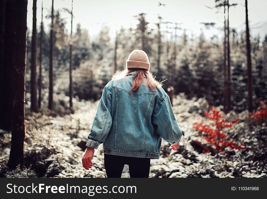 Woman Wearing Blue Denim Jacket and White Beanie Walking in the Forest