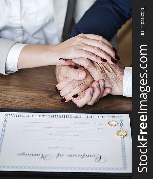 Man and Woman Holding Hands on Brown Wooden Table