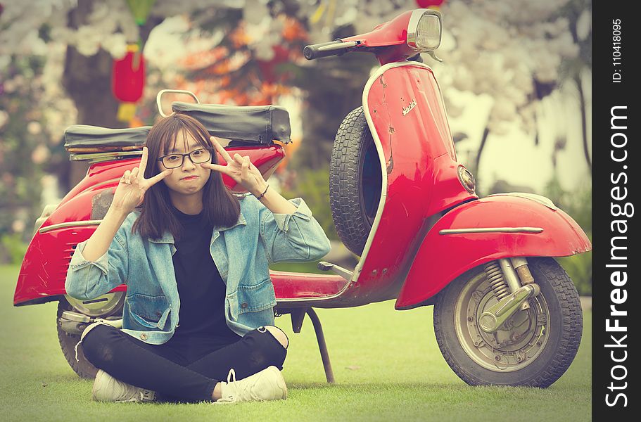 Girl Doing Peace Sign Indian Sitting in Front of Red Scooter Motorcycle