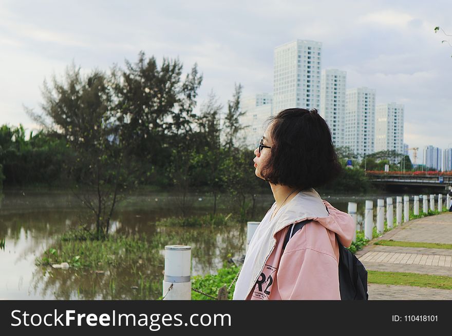 Woman Wearing Pink Hoodie Stand In Front Of Body Of Water