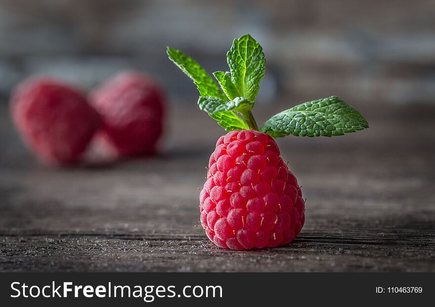 Ripe raspberries and mint on a brown wooden background