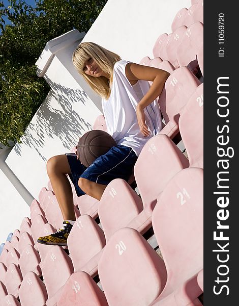 Teenage blond girl waiting for a basketball match in the fan area. Teenage blond girl waiting for a basketball match in the fan area