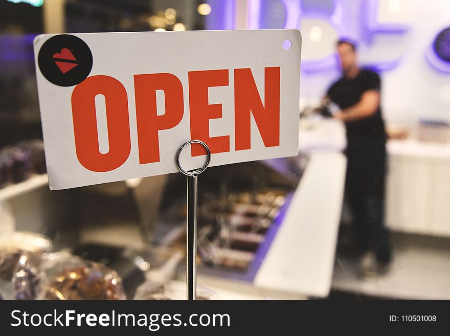 Shallow Focus Photography of Red and White Open Signage Near Man Wearing Black Shirt