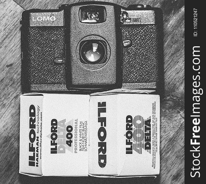 Black Lomo Compact Camera Beside Ilford Delta 400 Black & White Film Box