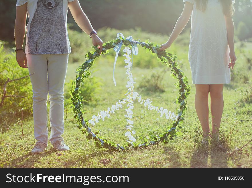 Two Person Holding White and Green Peace Wreath