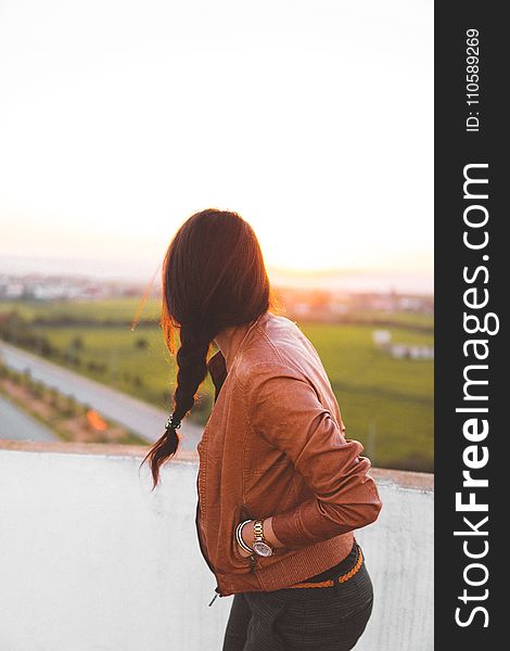 Woman Wearing Brown Leather Jacket Standing And Looking On Grass Field View At Day Time