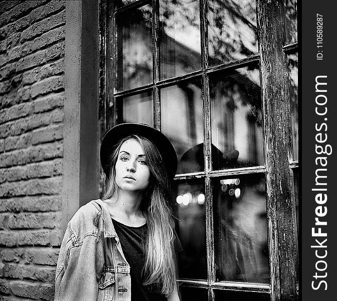 Grayscale Photo of Women&#x27;s Denim Jacket and Hat Leaning on Window