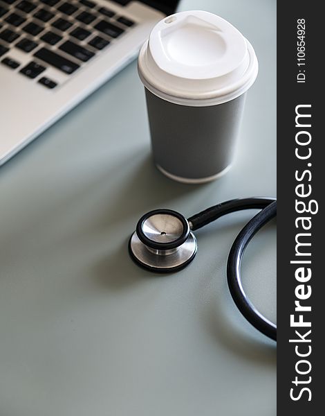 Black Stethoscope Beside Gray Disposable Cup