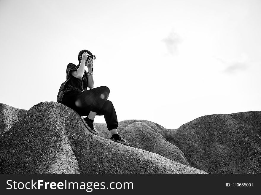 Person Sitting on Rocks Taking Photos