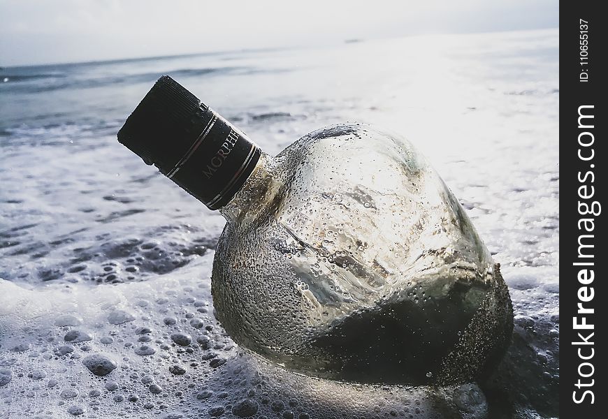 Clear Glass Bottle on Body of Water