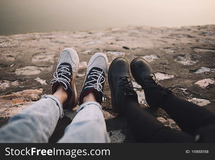 Two Person Wearing Pants and Shoes Sits on Ground at Daytime