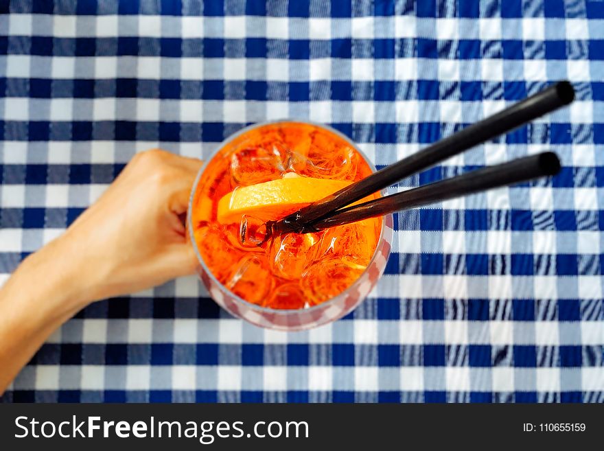 Person Holding Clear Drinking Glass With Two Black Straws