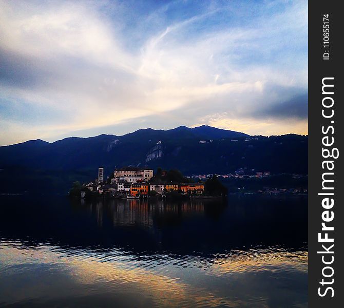 Buildings Near Body Of Water And Mountain