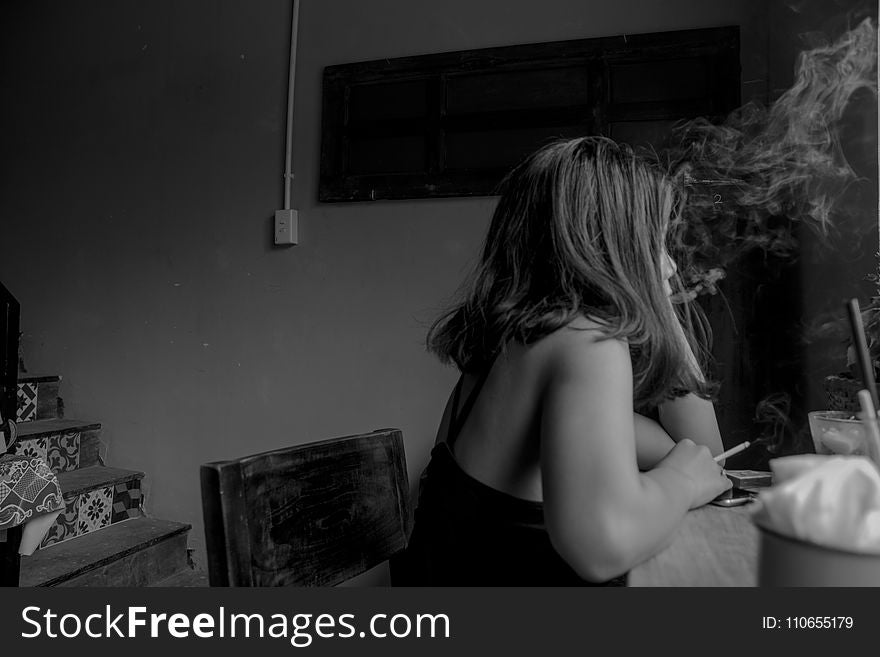 Grayscale Photo of Woman Sitting on Chair Near Chair