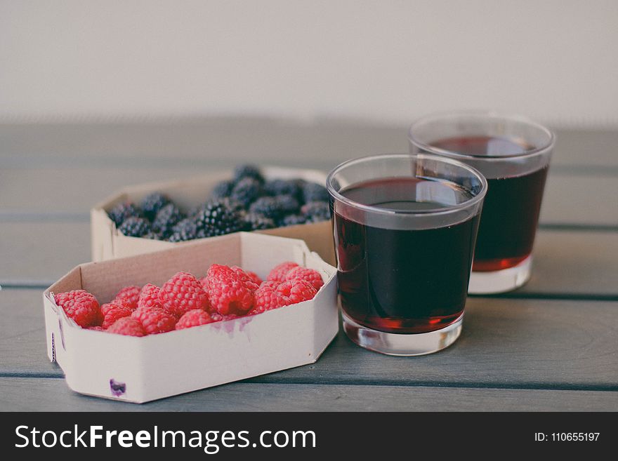 Two Drinking Glasses Filled With Raspberry and Blueberry Fruit Juices