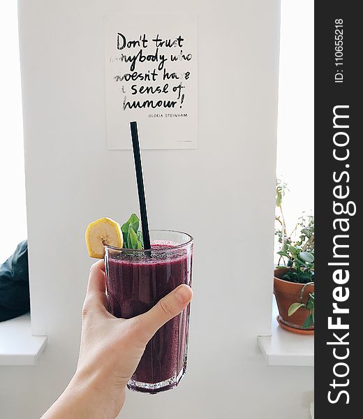 Person Holding Clear Drinking Glass With Purple Smoothie With Quotation Decor