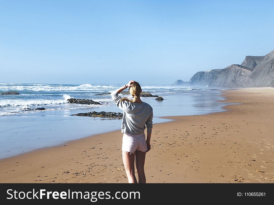 Woman in Gray Long-sleeved Shirt With Pink Short Shorts Standing Near Sea