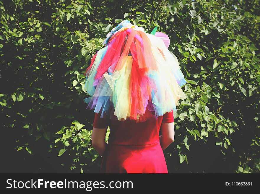 Adorable girl in rainbow dress on her head playing outdoors