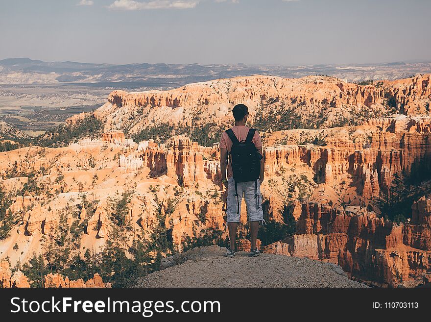 Young man standing by the scenic view of stunning red sandstone hoodoos in Bryce Canyon National Park in Utah, USA