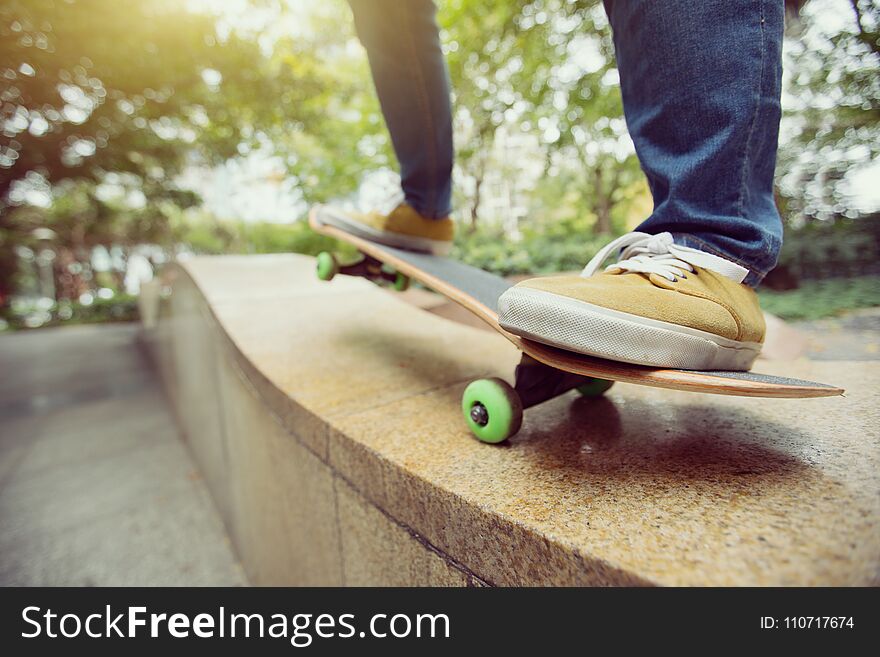 Skateboarder legs riding skateboard at city skatepark