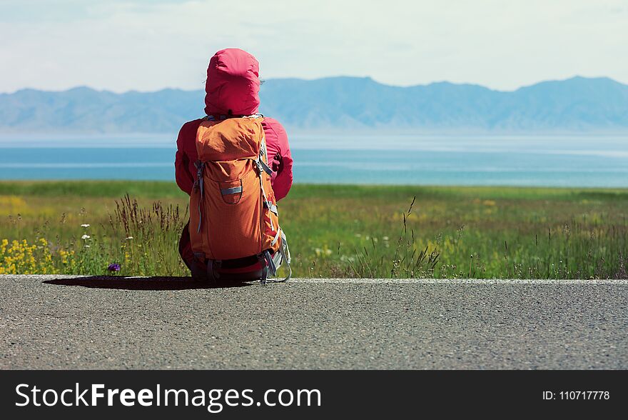 Backpacker Sit On The Roadside Of Country Road