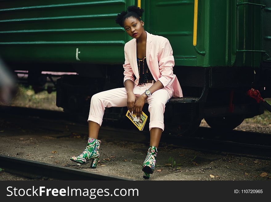 Woman In Pink Blazer Sitting On Green Train