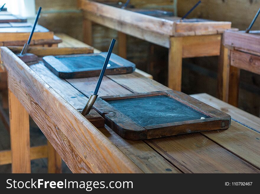 Old classroom with antique chairs and desks with little slate tablets on desks for writing in chalk. Old classroom with antique chairs and desks with little slate tablets on desks for writing in chalk.