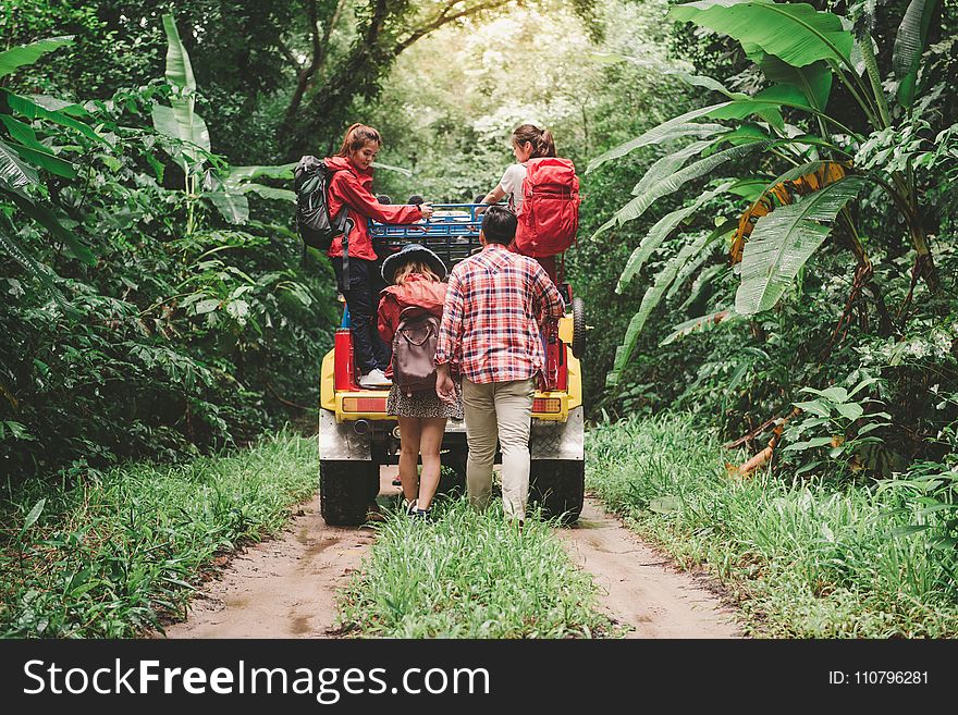 Two Person Riding On Yellow Suv And Man And Woman Walking Behind It