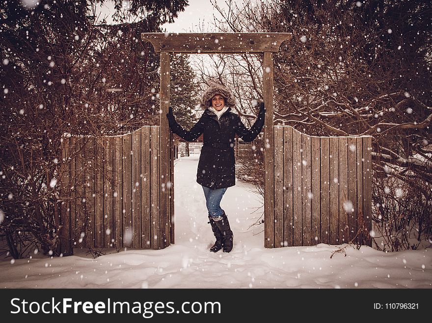 Woman in Black Coat Beside Fence during Snow