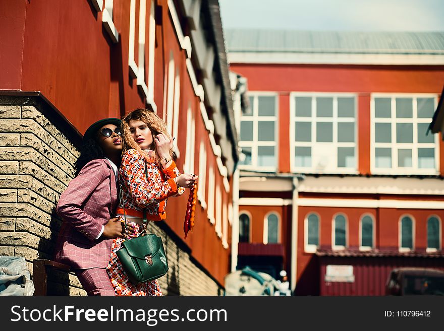 Selective Focus Photographed of Woman Wearing Orange and White Floral Dress and Man Wearing Maroon Suit