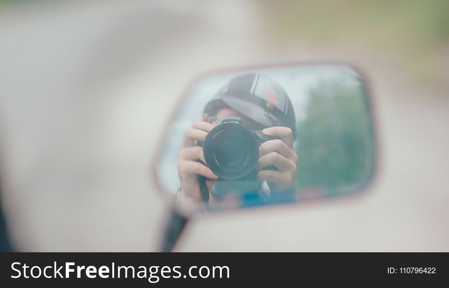 Shallow Focus Photography of Person Holding Dslr Camera in Mirror Reflection
