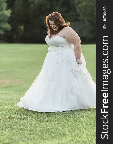 Woman in White Floral Wedding Gown Walks on Green Grass Lawn Yard