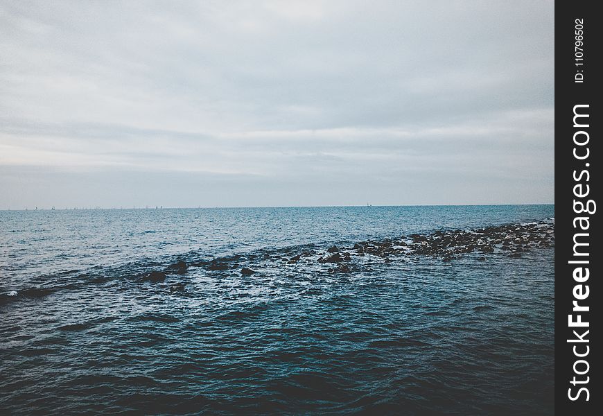 Photography of Ocean Under Cloudy Sky