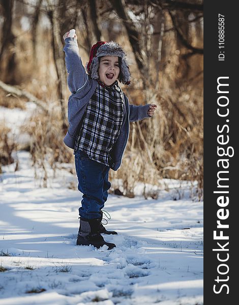 Boy in Gray Jacket and Blue Jeans Standing on Snow Outdoor