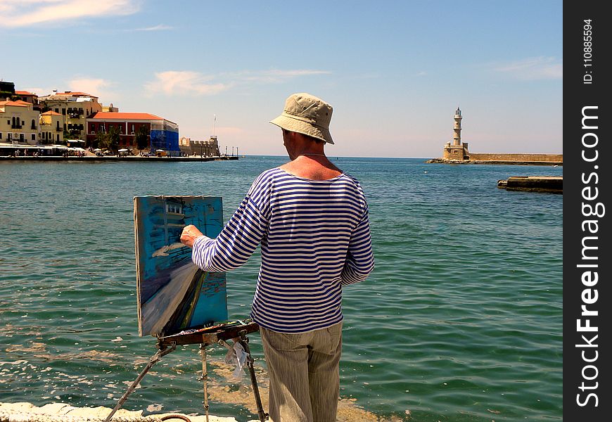 Man in White and Blue Striped Long-sleeved Shirt Painting Near Seashore