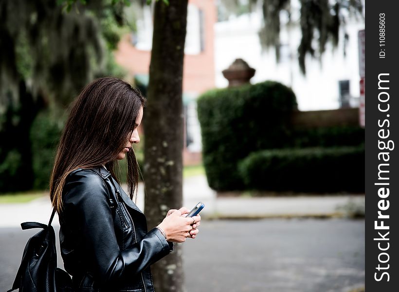 Woman in Black Leather Jacket Holding Smartphone
