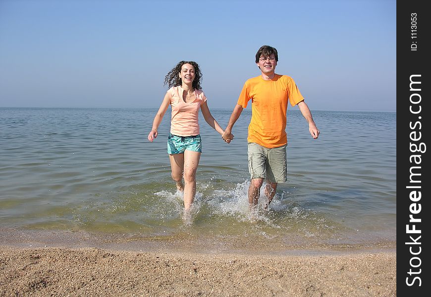 Couple run on beach from sea