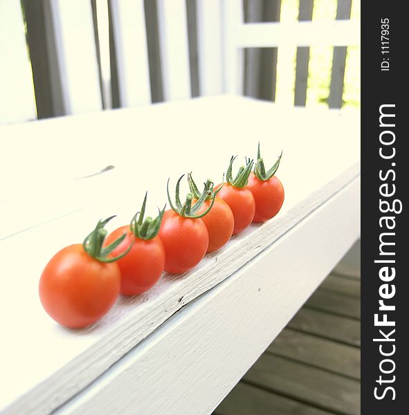 Red cherry tomatoes on an outdoor bench. Red cherry tomatoes on an outdoor bench