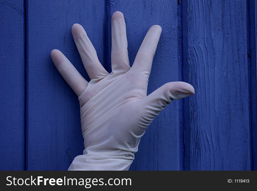 A hand in rubber glove on blue background