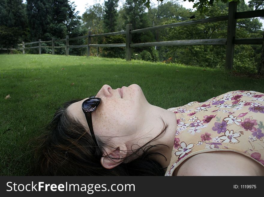 Woman in sunglasses lying down on green lawn. Woman in sunglasses lying down on green lawn