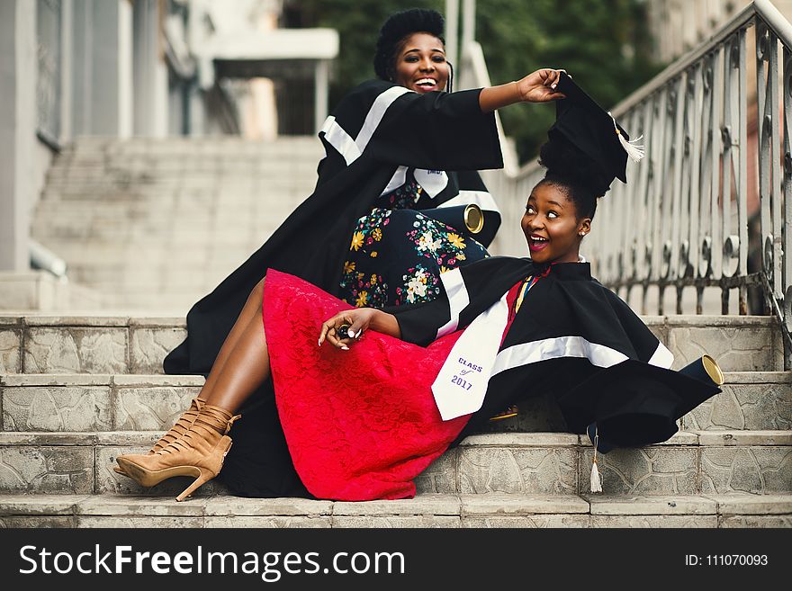 Shallow Focus Photography of Two Women in Academic Dress on Flight of Stairs